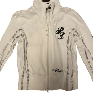 Lonsdale kofta - Super snygg vit kofta från Lonsdale med snygga silver detaljer och skrift på ryggen🫶🏻 Aldrig använt och är i nyskick, koftan är en turtleneck 💗