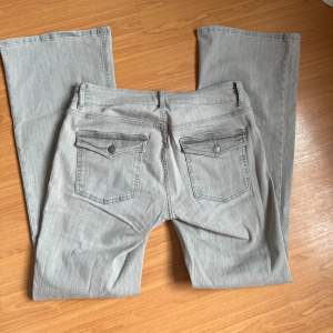 Fina ljusgråa Low waist (lågmidjade) bootcut jeans från Nelly med fina knappar på fickorna baktill🩶🩶  Använda 1 gång men insåg att de va för stora därav säljer jag dom☺️  Helt slutsålt på hemsidan  Finns även en annons på vinted🩵