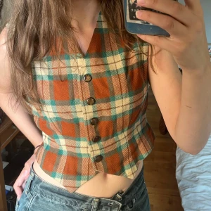 Rutig vintage väst - Rödbrun & grön rutig vintage väst! 60/70 tals stil i väldigt bra skick!🫶 Fungerar även som ”topp” om man inte vill ha något plagg under! (som på bild).