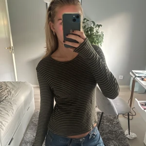 Randig långärmad tröja - Säljer en superfin randig tröja i grönt och svart. Den är långärmad och har en tight passform som sitter perfekt. Perfekt för höst och vår när det är lite kyligare ute. Passar både till jeans och kjol!