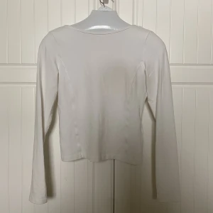 Tröja med öppen rygg  - Vit långärmad tröja med djup rygg. Den kramar om kroppen väldigt fint!