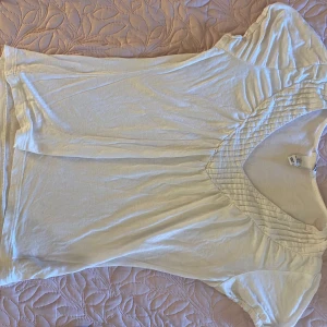 Vit t-shirt i riktigt soft material  - Super skön med lite små detaljer och v ringad 