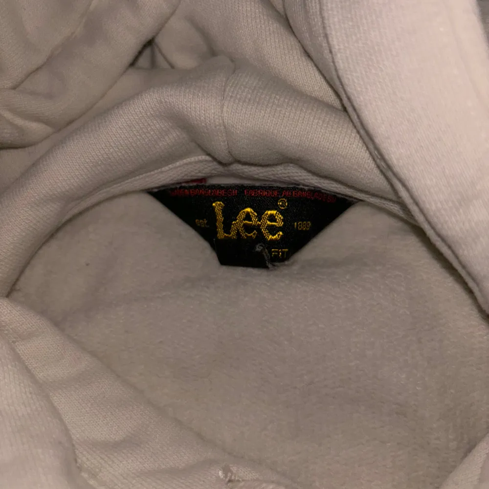 Säljer en snygg och bekväm vit hoodie från Lee. Den har en klassisk design. Perfekt för en avslappnad stil och passar till alla tillfällen. Märket Lee är broderat på framsidan för en stilren look.. Tröjor & Koftor.