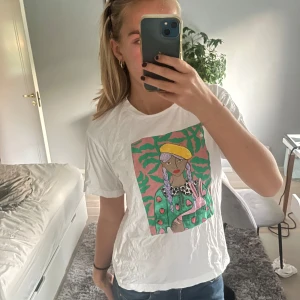 Vit t-shirt med färgglatt tryck - Säljer en vit t-shirt med ett supercoolt och färgglatt tryck på framsidan. lite skrynklig men fint skick!