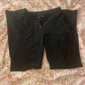 Juicy Couture Byxor - Säljer nu mina juicy couture byxor i XS i färgen Black. De är i bra skick förutom att metall saken lossnat på ena snöret, noppriga på insidan i midjan, små fläckar (se bild) och samt att de är sträva vid knäna och vid fickorna där bak!❤️Säljer för 300