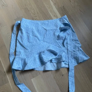 Blå kjol - Blå kjol med vita små söta blommor på som man knyter omlott💙