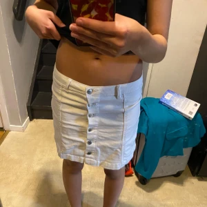 Vit jeanskjol från Perfect Jeans - Säljer en superfin vit jeanskjol från Perfect Jeans i storlek 36. Kjolen har en rad med snygga knappar framtill och är perfekt för sommardagar. Den är i nyskick och passar både till vardags och fest. 🕶️✨