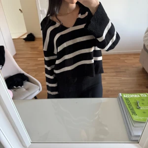 Svart och vit randig tröja - Säljer en svart och vit randig tröja med v-ringad hals. Tröjan har långa ärmar och en lös passform, perfekt för en avslappnad stil.