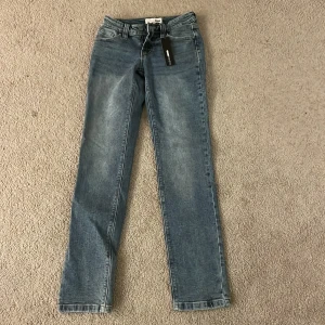 Blå jeans från Fashion Nova - Snygga blå jeans från Fashion Nova med en klassisk straight fit. De har en dragkedja och knapp framtill samt fem fickor. Perfekta för en stilren look. Aldrig använt prislappen är kvar 