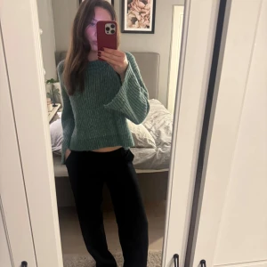 Grön stickad tröja - Säljer en mysig grön stickad tröja med croppad passform. Tröjan har långa ärmar och en rund halsringning. Den har även en slitt vid ärmarna och vid magen. 