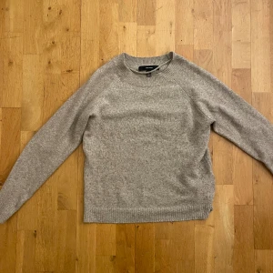 Beige stickad tröja från vero Moda - Säljer en stilren beige aktig stickad tröja från vero Moda. Tröjan har långa ärmar och en rund halsringning. Den är mjuk och bekväm, idealisk för både vardag och avslappnade tillfällen.