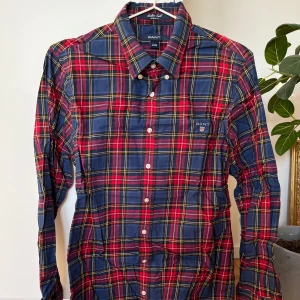 Rutig skjorta från GANT - Snygg rutig skjorta från GANT i blått, rött och gult. Skjortan har långa ärmar och knappar framtill. Perfekt för en avslappnad stil med sin casual fit. Broderad logga på bröstet ger en extra touch.