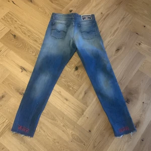 Blå jeans från Replay - Snygga blå jeans från Replay med en cool tvättad look. De har en klassisk femficksdesign och fransade benslut för en trendig touch. Perfekta för en avslappnad stil. Modell är maddiespa. 