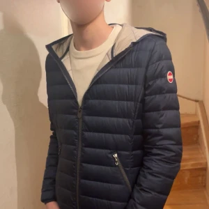 Mörkblå pufferjacka från Colmar - Säljer en snygg mörkblå pufferjacka från Colmar med dragkedja och huva. Jackan har långa ärmar och två praktiska fickor med dragkedja. Perfekt för kyligare dagar! Storlek 44/xs