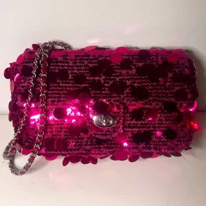 Rosa paljettväska Ibiza vibe - Snygg rosa axelväska täckt med glittrande paljetter och en elegant kedjerem. Perfekt för att lysa upp vilken outfit som helst. Väskan har en stilren låsdetalj framtill.