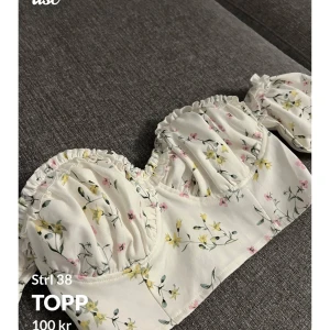 Blommig offshoulder topp från Missguided - Säljer en söt blommig offshoulder topp från Missguided. Toppen har volangdetaljer och en dragkedja bak. Perfekt för sommarens varma dagar med sitt lätta och luftiga material.