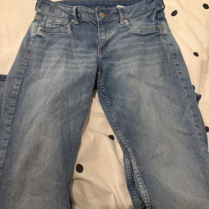 Blå låg midjade jeans - Snygga blå jeansbyxor med klassisk femficksdesign. De har en knapp och dragkedja framtill. Perfekta för en avslappnad stil.
