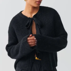 Svart stickad kofta med knytband - Säljer en svart stickad kofta med knytband framtill. Säljer eftersom är inte nöjd med köpet, är ej använd 