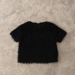Svart fluffig topp från Zara - Säljer en svart fluffig topp från Zara. Den har korta ärmar och en unik textur som ger en cool look. Perfekt för att lägga till lite extra stil till din garderob.