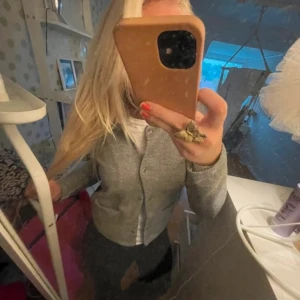 Grå kofta med knappar - Säljer en stilren grå kofta med knappar framtill. Perfekt för lager-på-lager och passar till många olika outfits. Koftan har långa ärmar och en klassisk design.