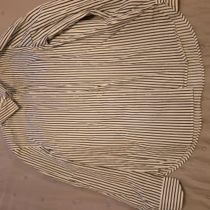 Randig skjorta från H&M - Snygg vit och svart randig skjorta från H&M. Skjortan har långa ärmar och knappar framtill. Perfekt för en stilren look. 🖤🤍