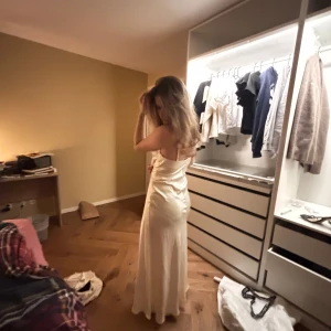 Champagnefärgad långklänning - Elegant champagnefärgad långklänning med omlott-design och smala axelband. Perfekt för en speciell kväll med sin vackra och flytande siluett.