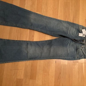 Blå jeans från Lee - Säljer ett par klassiska blå jeans från Lee. De är bootcut och är lågmidjade! De är tillverkade i denim med en dragkedja och knapp framtill. Perfekta för en avslappnad stil. Helt nya med prislapp!