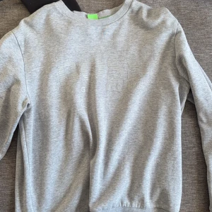 Grå sweatshirt från hugo boss - Säljer en stilren grå sweatshirt från hugo boss. Tröjan har en rund halsringning och långa ärmar. Perfekt för en avslappnad look. Passar bra till jeans eller joggers.