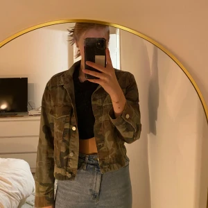 Camouflagejacka från Perfect Jeans - Säljer en camouflagejacka från Perfect Jeans. Jackan har en klassisk krage och knappar framtill. Perfekt för en avslappnad stil och passar bra till jeans. Den har långa ärmar och en croppad passform.