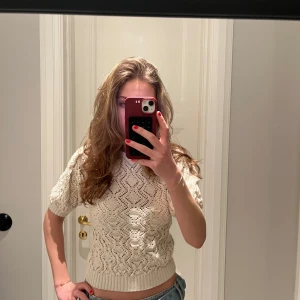 Kräm vit stickad kortärmad tröja - Säljer en söt kräm vit/off-white stickad tröja med korta ärmar och ett fint mönster ifrån Zara. Perfekt inför sommarn när man vill ha något som är lite varmare men ändå inte så att de blir för varmt ☀️. Tröjan har en ribbad nederkant som ger en snygg passform. Storleken är M men passar S