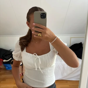Vit gullig topp - En vit gullig topp från Gina med rosett och ärm. 
