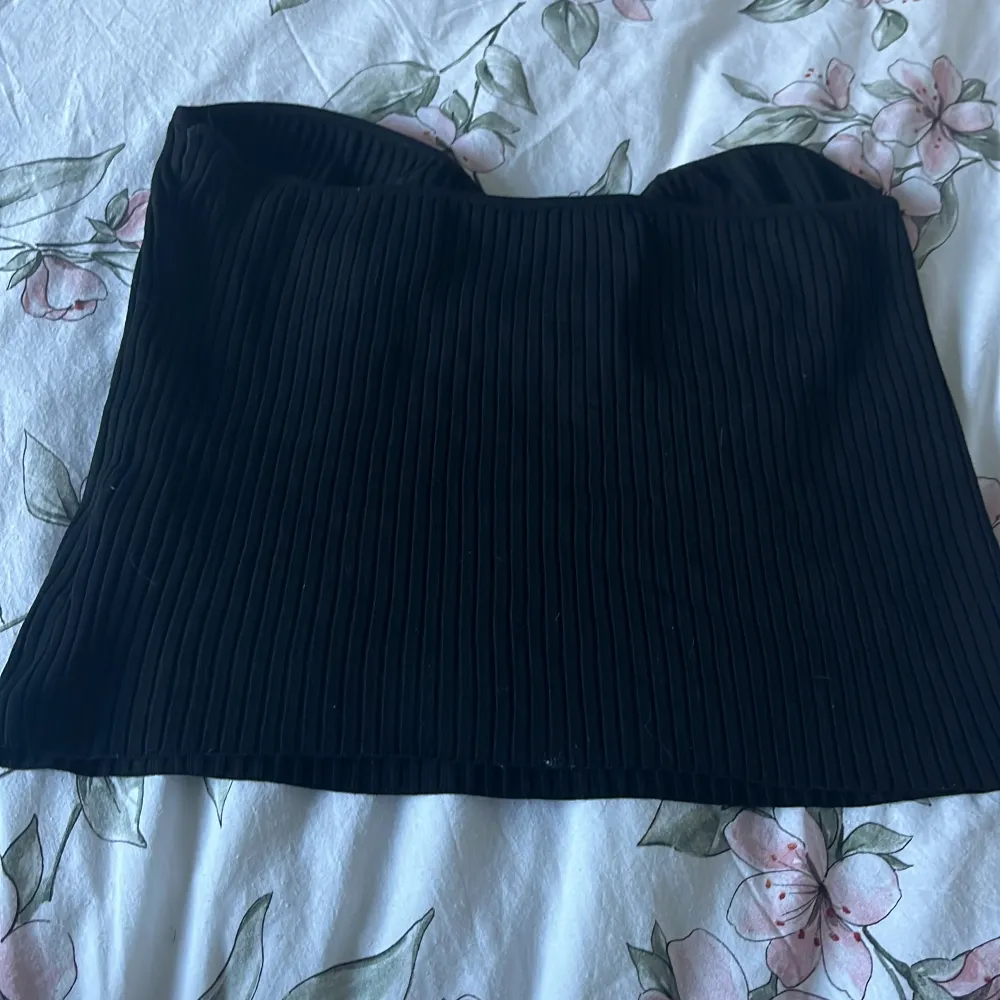 Säljer en snygg svart ribbad tubtopp från Lindex. Perfekt för en kväll ute eller som en stilren bas i garderoben. Toppen är i storlek L!. Yläosat.