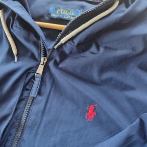 Ralph Lauren jacka - Säljer denna skitsnygga windbreaker jacka från Ralph Lauren, perfekt nu till hösten/våren. Har sällan använt den eftersom den var lite för stor. Köpt på plick så har ej kvitto.