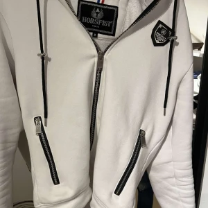 Vit jacka från Horspist - Hej! Nu säljer jag min snygga horspist zip up hoodie. 10/10 nyskick ingen skada på hoodien.  Nypris ligger på 2500. 