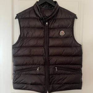 Moncler Gui Väst - Mörkbrun Moncler Gui väst köpt från Garms Market | Storlek = 2 fits S | Skick = 8/10 2st små defekter | Pris = 🚨2299kr🚨 | 50kr rabatt om du följer mig🌟 | Tveka inte på att höra av dig vid frågor eller funderingar🙌
