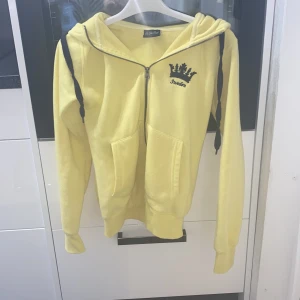 Gul hoodie från On The Peak - Säljer en superfin gul hoodie från On The Peak i storlek XS. Den har en dragkedja framtill och en snygg broderad krona med texten 'Sweden' på bröstet. På huvan står det också 'Sweden' broderat. Perfekt för en casual look!❤️pris kan diskuteras