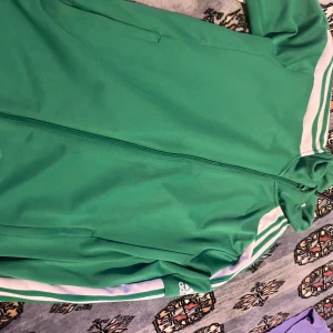 Grön adidas zip up - En najs grön adidas zip up med någon lten fläck längst nere, även någon tråd som sticker ut. 