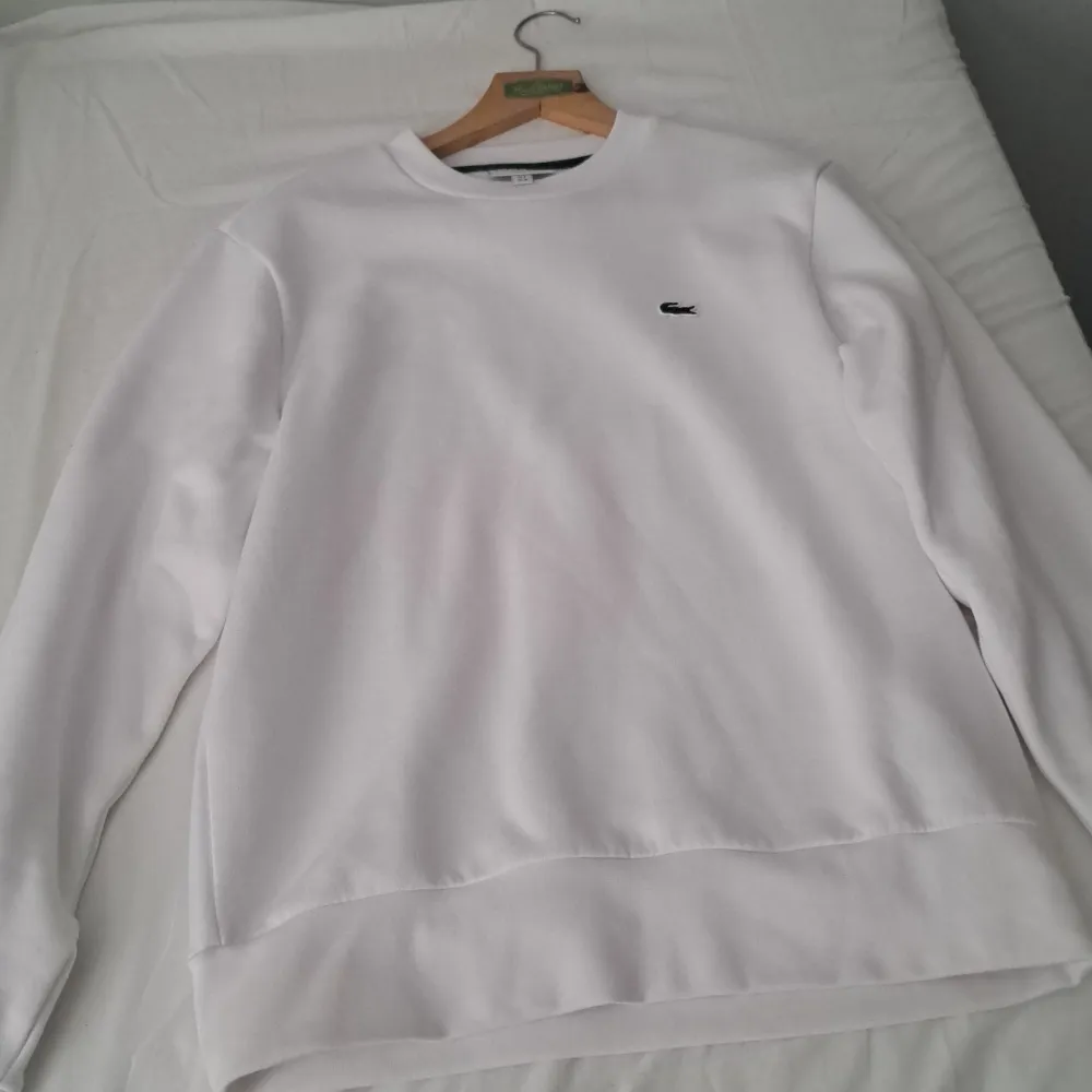 Säljer en stilren vit sweatshirt från Lacoste i storlek M. Skick 10/10 köpt på boozt för 1150 kr. Avänd en gång. Säljer då den inte passar mig. Vid frågor tveka inte att höra av dig!. Tröjor & Koftor.