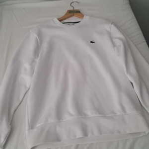 Vit sweatshirt från Lacoste - Säljer en stilren vit sweatshirt från Lacoste i storlek M. Skick 10/10 köpt på boozt för 1150 kr. Avänd en gång. Säljer då den inte passar mig. Vid frågor tveka inte att höra av dig!