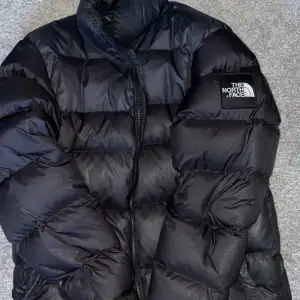 En svart The North Face jacka i storlek M, har ett märke på ryggen och ett på sidan av armen. Bra skick föutom att dragkedjan fastnar i tyget så det har gått upp vid fickan men det är inget som syns då det är inåt. KOLLA SISTA BILDEN!