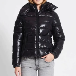 Svart pufferjacka - Säljer en snygg svart pufferjacka i glansigt material. Perfekt för kalla dagar med sin varma vaddering och långa ärmar. Jackan har en dragkedja framtill och en hög krage för extra skydd mot kylan. Passar perfekt till både vardag och vinteraktiviteter. 🖤 Helt ny bara testad 