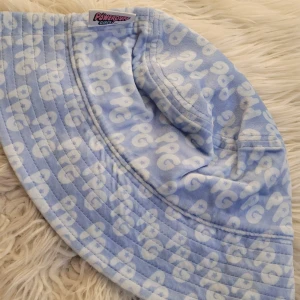 Blå Powerpuff Girls hatt - Superfin blå hatt med Powerpuff Girls-tema från H&M. Den har ett mönster med vita bokstäver och är gjord i ett mjukt material. Perfekt för att ge en lekfull touch till din outfit!