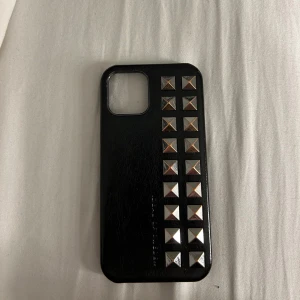 Svart mobilskal med nitar från Ideal of Sweden - Snyggt svart mobilskal från Ideal of Sweden med coola silverfärgade nitar på baksidan. Perfekt för att ge din mobil en edgy look samtidigt som den skyddas. Skalet är i mycket bra skick och passar perfekt för dig som gillar en stilren men ändå tuff design.