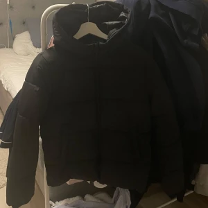 Svart pufferjacka med huva - Säljer min superfina svarta pufferjacka i bra skick. Den är perfekt för kalla vinterdagar och är varm. Jackan är endast använd under en vinter!🤍