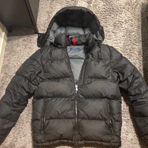 Svart pufferjacka från Polo Ralph Lauren - Säljer en svart pufferjacka från Polo Ralph Lauren i storlek S. Den är i bra skick med en liten defekt på armen och väldigt varm. Perfekt för vintern! 