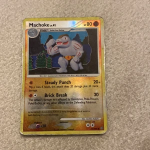 Machoke Pokémonkort - Säljer ett Machoke Pokémonkort med 80 HP. Kortet har attacker som Steady Punch och Brick Break. Det är i bra skick och perfekt för samlare eller spelare som vill stärka sin kortlek. Kortet har en glansig yta och är en del av en äldre samling.