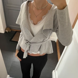 Grå stickad kofta med snörning  - Grå stickad omlottkofta från Sportscraft i storlek M, passar även S. Använd gärna köp nu!