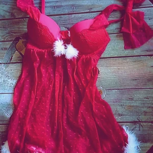 Röd julinspirerad babydoll med spets och rosett - Säljer en oanvänd röd babydoll med julkänsla! Den har spetsdetaljer och en söt rosett som går att ta av eller fästa på båda banden. Klänningen är dekorerad med vita fluffiga detaljer och har en prickig design. Den är i storlek 75A. Perfekt för julfirandet eller en festlig kväll. 🎄✨