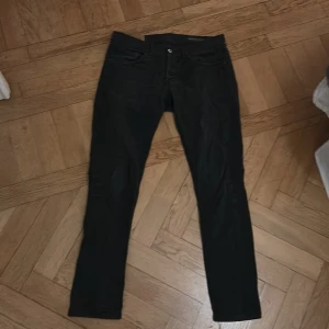 Svarta jeans från Dondup - Säljer ett par snygga svarta jeans från Dondup, tillverkade i Italien. De har en klassisk design med fem fickor och knappgylf. 