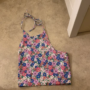 Blommig halterneck topp från Bik Bok - Säljer en superfin blommig halterneck topp från Bik Bok i storlek S. Toppen har ett färgglatt mönster med blommor i rosa, lila och blått. Perfekt för sommardagar eller festivaler! Den knyts i nacken och har en bekväm passform.